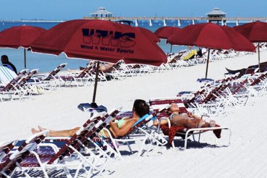 a group of people sitting at a beach umbrella in the snow