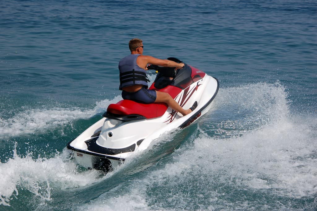 Jet ski a man riding a wave on top of a body of water