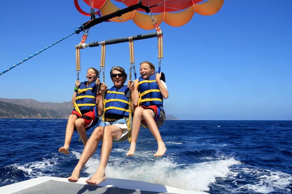 Happy Family Parasailing a man water skiing behind a boat